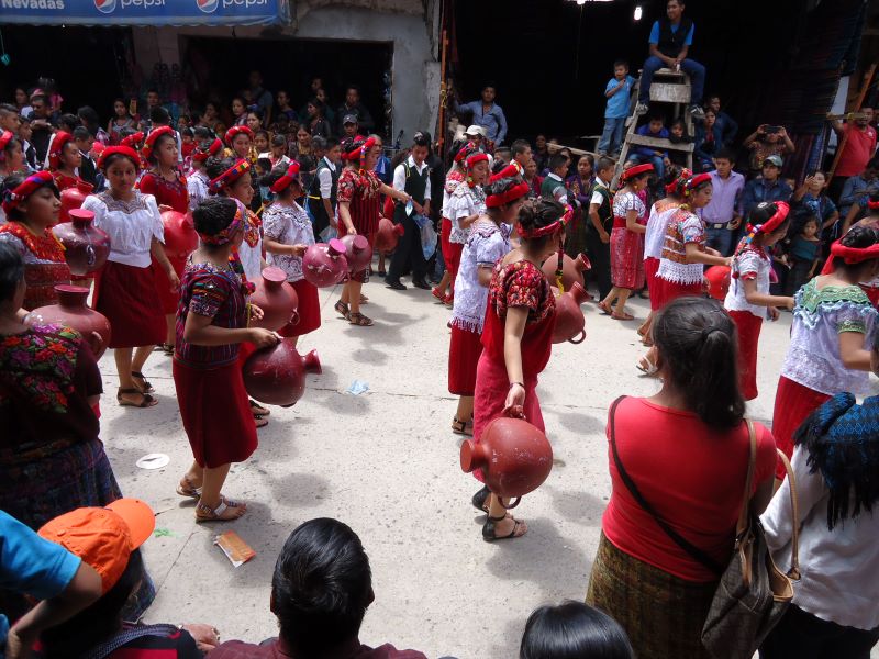 Mujeres q'anjob'ales con traje tradicional rojo y blanco cargando cántaros durante una fiesta en Barillas, Huehuetenango.